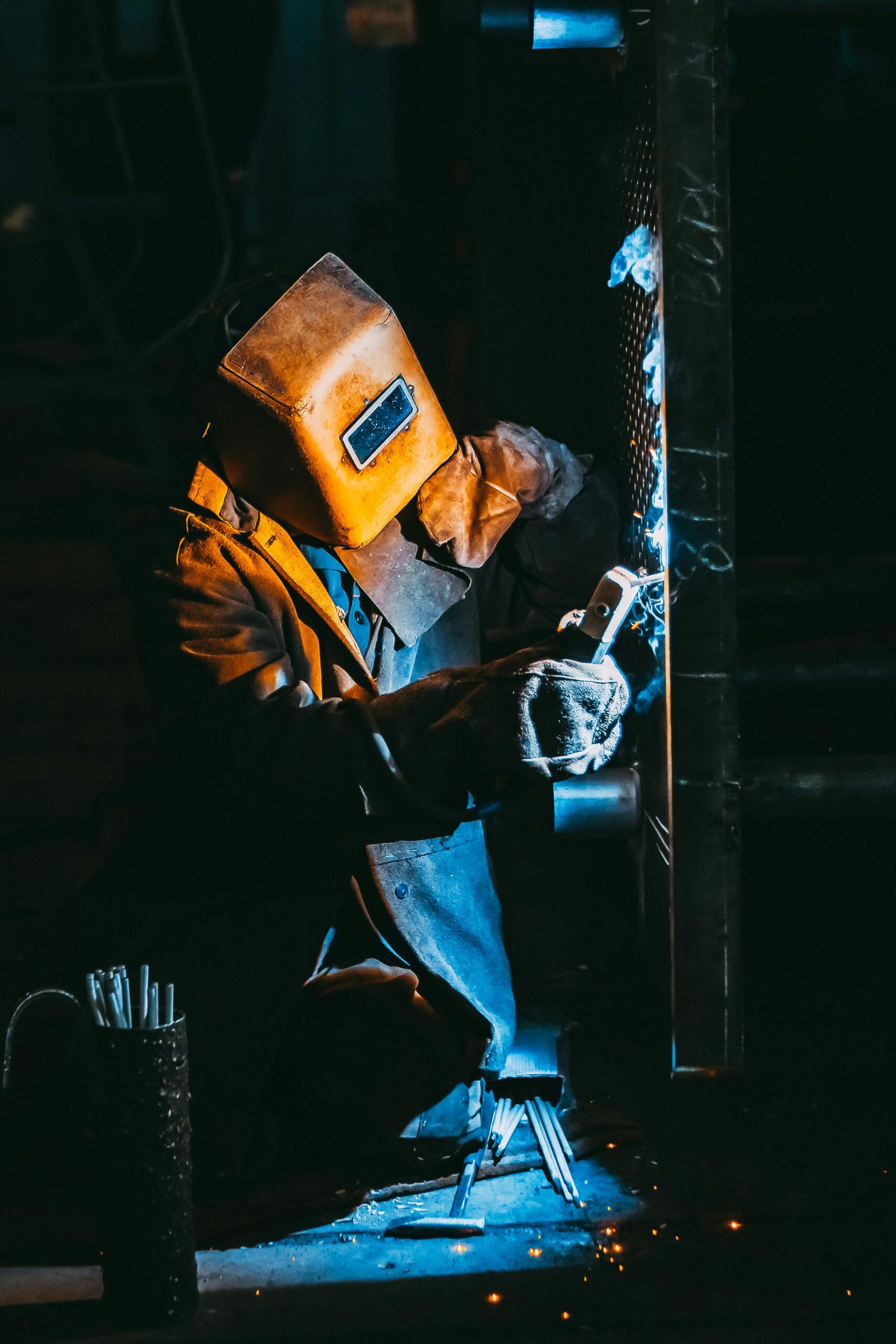 Industrial welder performing metal fabrication work in a manufacturing workshop